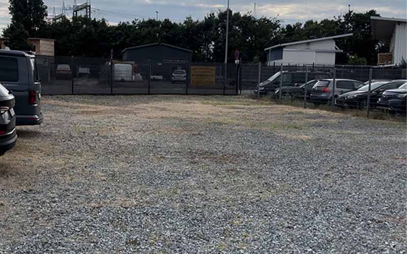 a gravel field with cars parked in the background