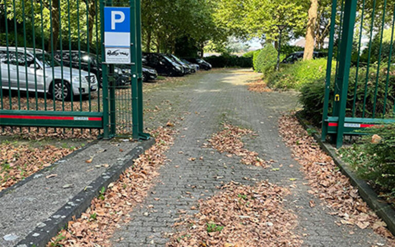 a parking lot with a gate and cars parked in the background